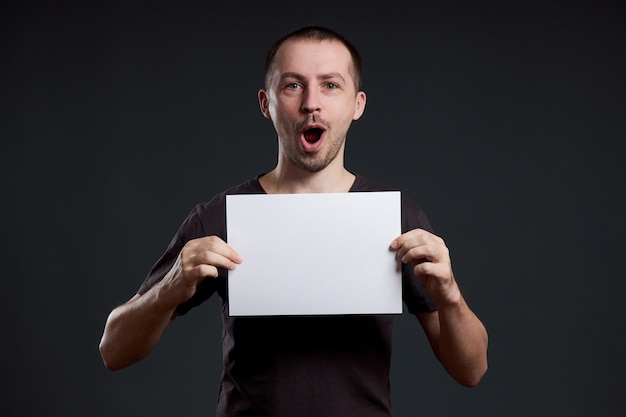Mann hält ein leeres Posterpapierblatt in seinen Händen. Lächeln und Freude, Platz für Text, Kopierraum