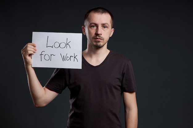 Mann hält ein Schild mit den Worten auf der Suche nach Arbeit, Arbeitslosigkeit und Krise