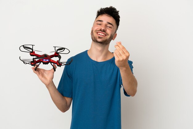Mann hält eine Drohne isoliert auf weißem Hintergrund und macht Geldgeste