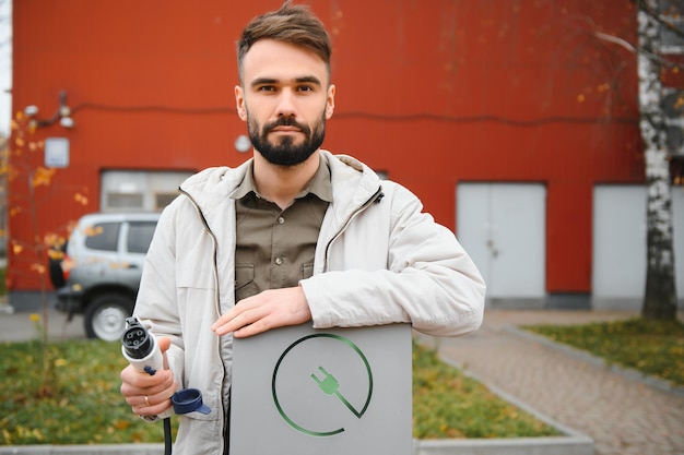 Mann hält Elektroauto-Ladegerät Elektrofahrzeug EV Ladestation und Ladegerät