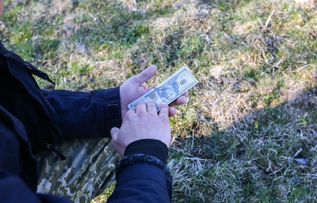 Mann hält Geld in den Händen draußen. Guy wirft Dollar in die Natur.