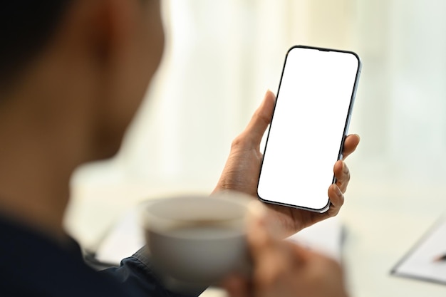 Mann hält Smartphone mit leerem Bildschirm für Ihre Werbe-SMS in der Hand über der Schulter, Nahaufnahme