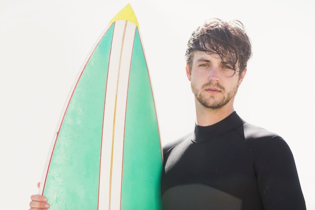 Mann hält Surfbrett am Strand