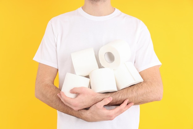 Mann hält Toilettenpapier auf gelbem Hintergrund. Hämorrhoiden-Konzept