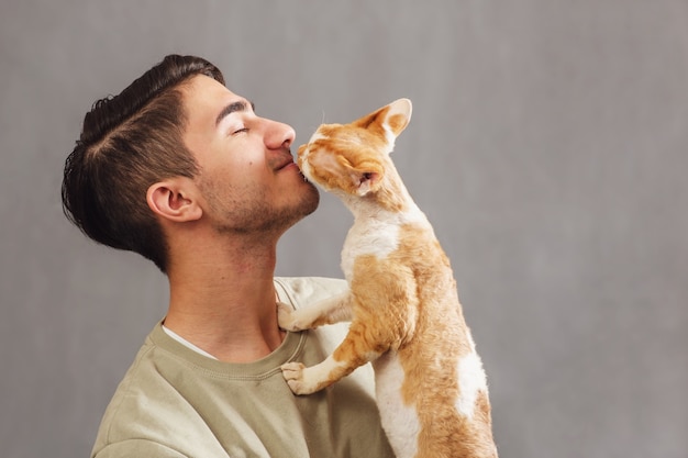 Mann hält und küsst Schnauze niedlich Devon Rex Katze