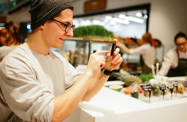 Mann halten das Smartphone auf Einkaufszentrumhintergrund