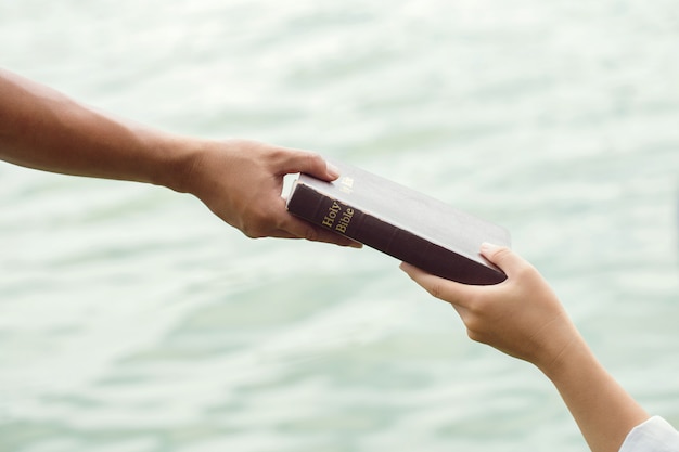 Mann Hand, die Frauen die Bibel gibt. Konzept des Gebens