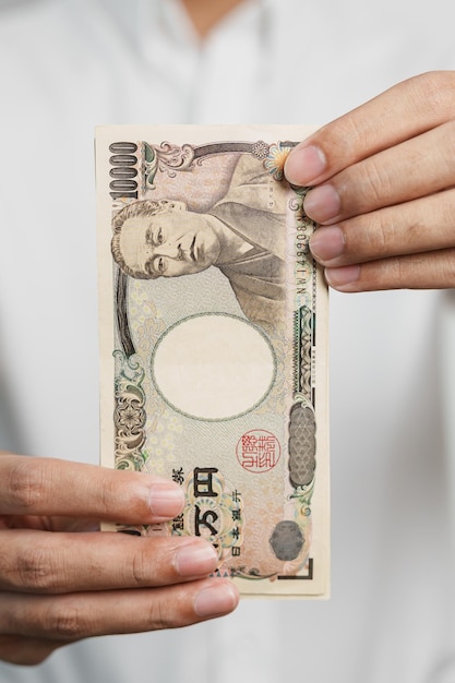 Mann Hand hält japanische Yen Banknote Stapel Tausend Yen Geld Japan Bargeld Steuerrezession Wirtschaft Inflation Investitionsfinanzierung und Einkaufszahlungskonzepte