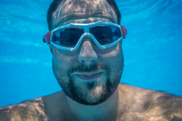 Mann hat Spaß im Schwimmbad Unterwasser lustiges Porträt Sommerurlaub