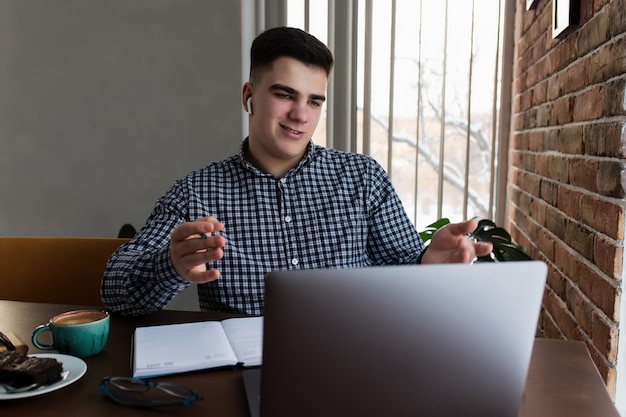 Mann hat Telefonkonferenz mit Laptop zu Hause, Kaffeetasse. Unscharfer Hintergrund. Hochwertiges Foto