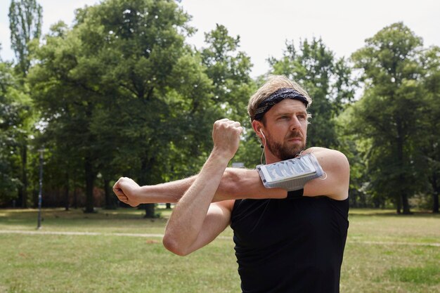 Foto mann hört musik, während er gegen bäume im park trainiert