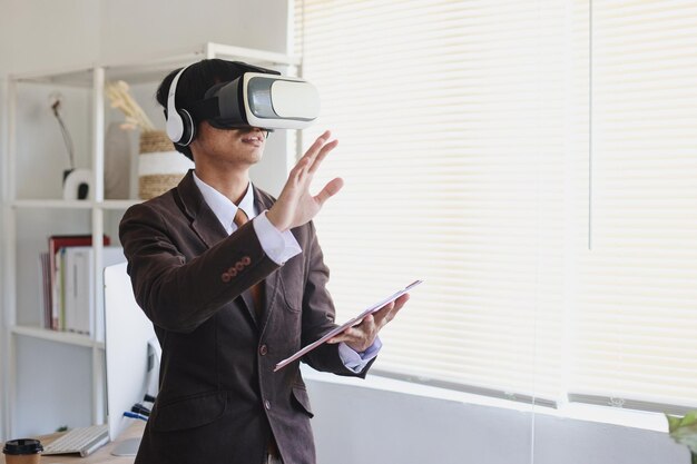 Mann im Anzug mit Virtual-Reality-Brille und Kopfhörern gestikuliert mit den Händen, als würde er etwas berühren
