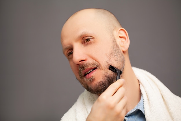 Mann im Badezimmer rasiert seinen Bart mit einem Rasiermesser