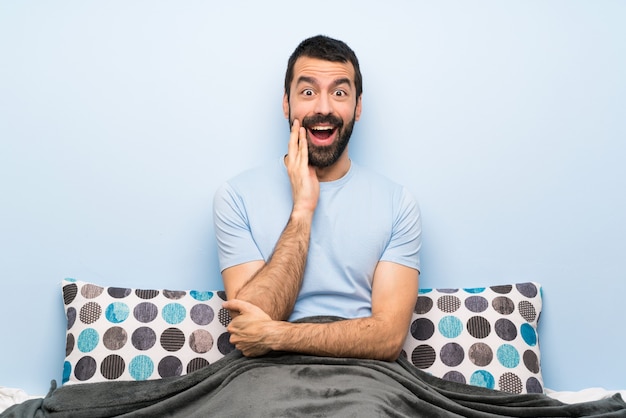 Mann im Bett mit Überraschung und entsetztem Gesichtsausdruck