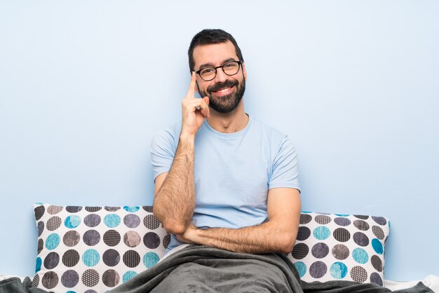 Mann im Bett mit Brille und glücklich