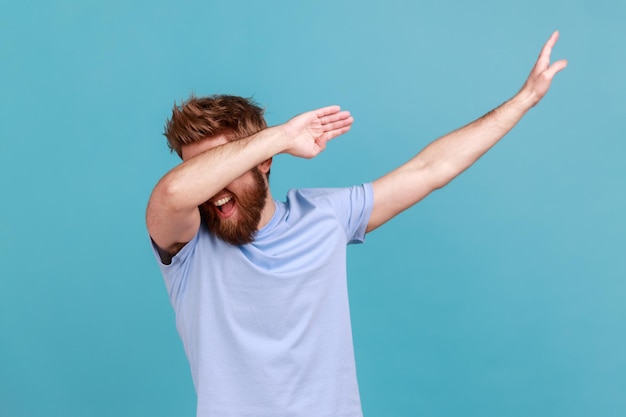 Mann im blauen T-Shirt mit Kleckstanz-Pose, berühmtem Internet-Meme des Triumphs