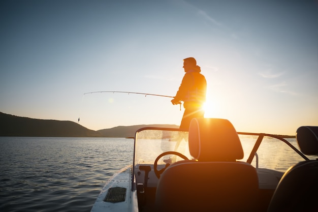 Mann im Bootsfischen bei Sonnenuntergang