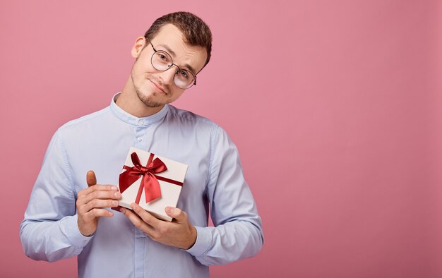 Mann im hemd hält geschenk im kasten und schaut gerade