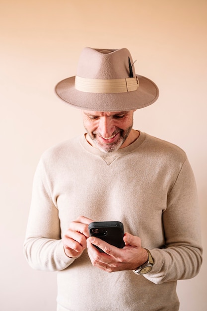 Mann im Hut mit Smartphone drinnen