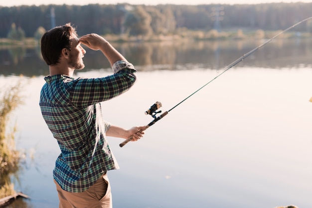 Mann im karierten Hemd, das auf Fluss im Sommer fischt.