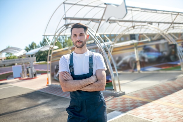 Mann im Overall beim Autoservice im Freien