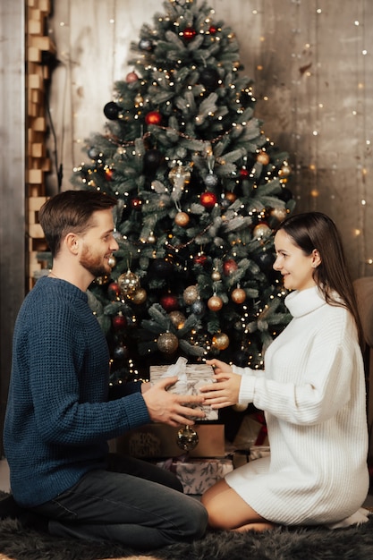 Mann im Pullover, der seiner Frau Weihnachtsgeschenküberraschung gibt.