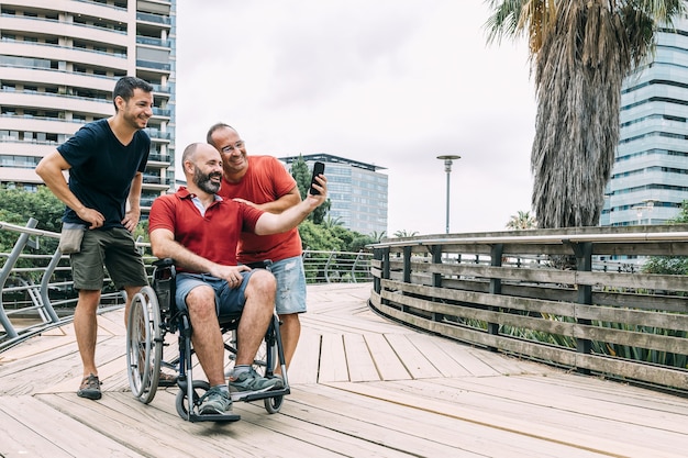 Mann im Rollstuhl, der ein Foto mit zwei Freunden macht