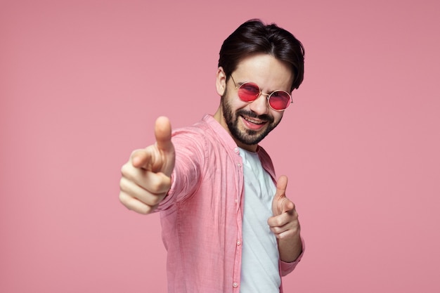 Mann im rosa Hemd und in der roten Sonnenbrille, die zeigende Geste zeigt