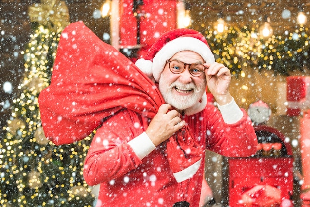 Mann im Schnee Bärtiger Mann, der Spaß in der Nähe von Weihnachtsbaum drinnen hat Weihnachtsmann-Winterporträt Weihnachtsvorbereitung