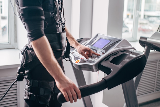 Mann im schwarzen Anzug für ems Training auf dem Laufband