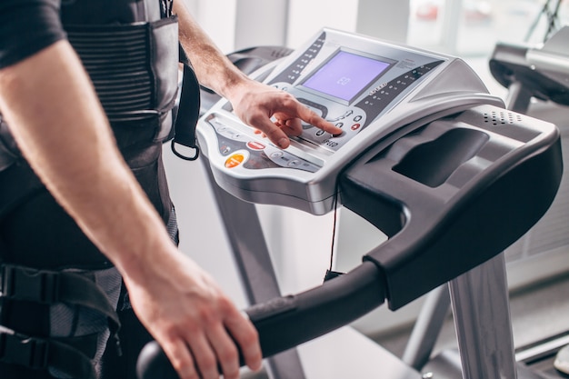 Mann im schwarzen Anzug für ems Training auf dem Laufband