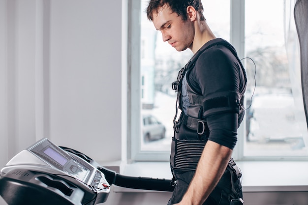 Mann im schwarzen Anzug für ems Training auf dem Laufband