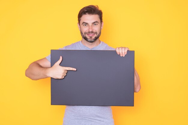 Mann im Studio, der ein leeres Promo-Brett zeigt, das mit dem Finger auf ein leeres Schild mit Copyspace zeigt