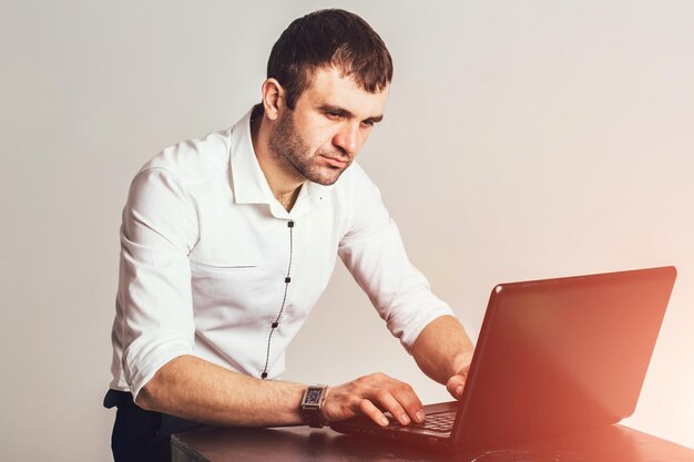Mann im weißen Hemd, der am Laptop auf hellgrauem Hintergrund arbeitet Closeup Geschäfts- und Managementkonzept
