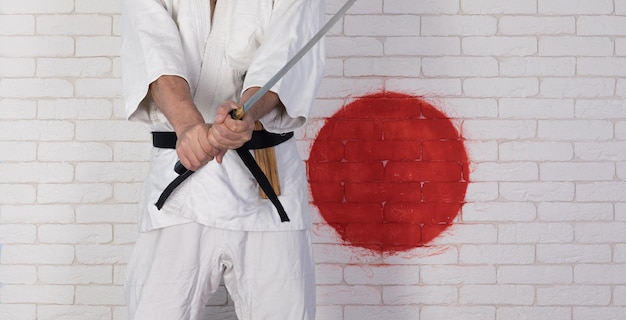 Mann im weißen Karate-Kimono mit Katana