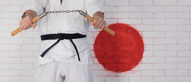 Foto mann im weißen kimono mit nunchakus