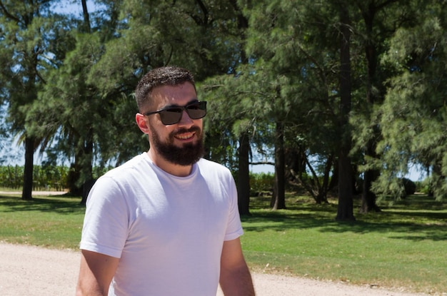 Mann im weißen T-Shirt Bart und Sonnenbrille auf dem Bauernhof lächelnd