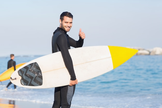 Mann im Wetsuit mit einem Surfbrett an einem sonnigen Tag