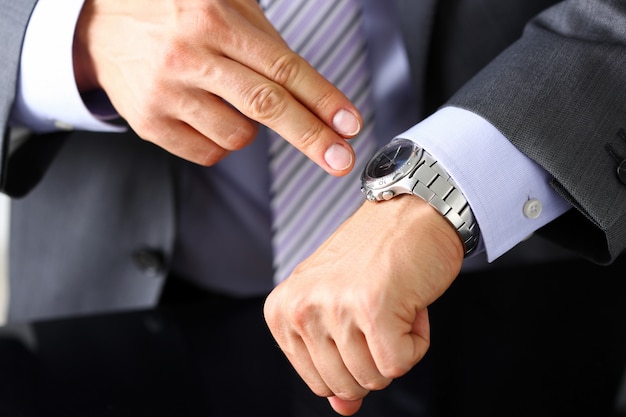 Mann in Anzug und Krawatte checken Zeit bei silberner Armbanduhr aus
