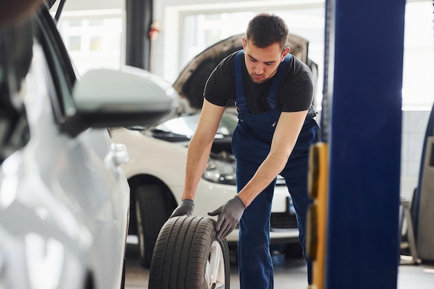 Mann in Arbeitsuniform, der das Autorad drinnen wechselt Konzeption des Automobilservices