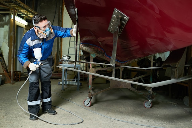 Mann in Atemschutzmaske, der Boote in der Zollwerkstatt malt