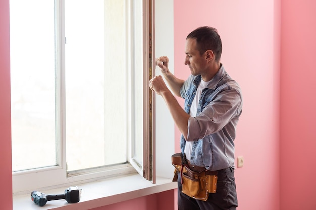 Mann in blauem Hemd macht Fensterinstallation.