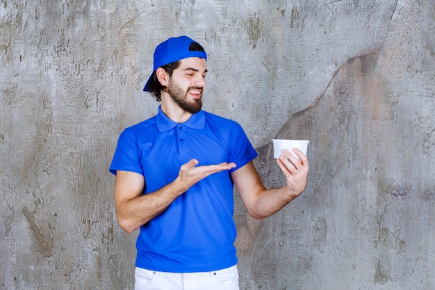 Mann in blauer Uniform mit einem Plastikbecher zum Mitnehmen.