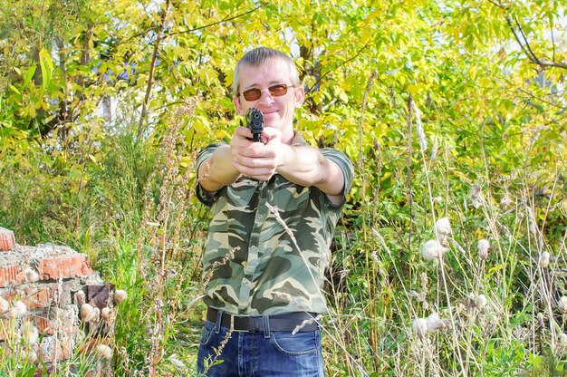 Mann in braunen Brillen mit Pistole in der Hand zielt