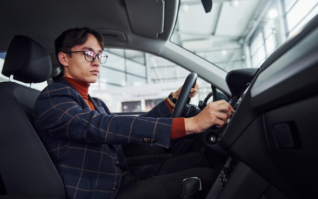 Mann in Brillen und formeller Kleidung, der in einem modernen Auto sitzt.