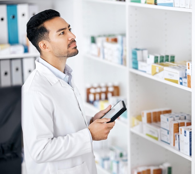 Mann in der Apotheke mit Tablet-Checkliste und Medikamentenvorrat mit Online-Webinformationen. Digitale Apotheker-App und Bestandssuche im Internet mit Scheck für Arzneimitteltechnologie oder Gesundheitswesen