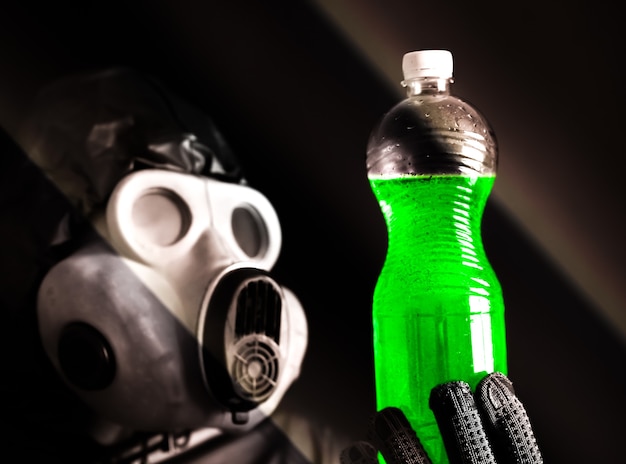 Mann in der Gasmaske, die Plastikflasche mit grünem Wasser hält Strahlungseinfluss. Umweltverschmutzung. Gefährliche Atomkraft. Ökologisches Desaster.