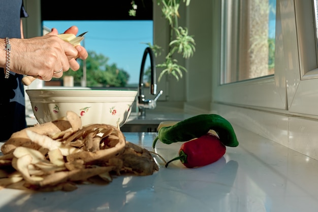 Mann in der Küche bereitet eine Mahlzeit zu, schält Kartoffeln und Gemüse, es werden keine Gesichter gezeigt