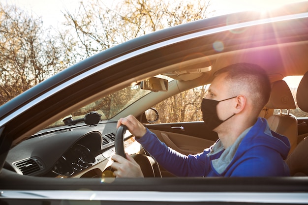 Mann in der medizinischen Maske, die ein Auto fährt