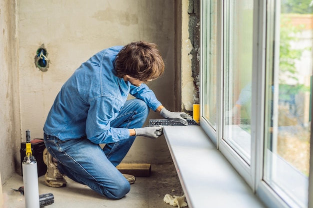 Mann in einem blauen Hemd macht Fensterinstallation.